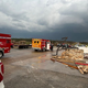 Emergency vehicles parked on a road next to a leveled building.
